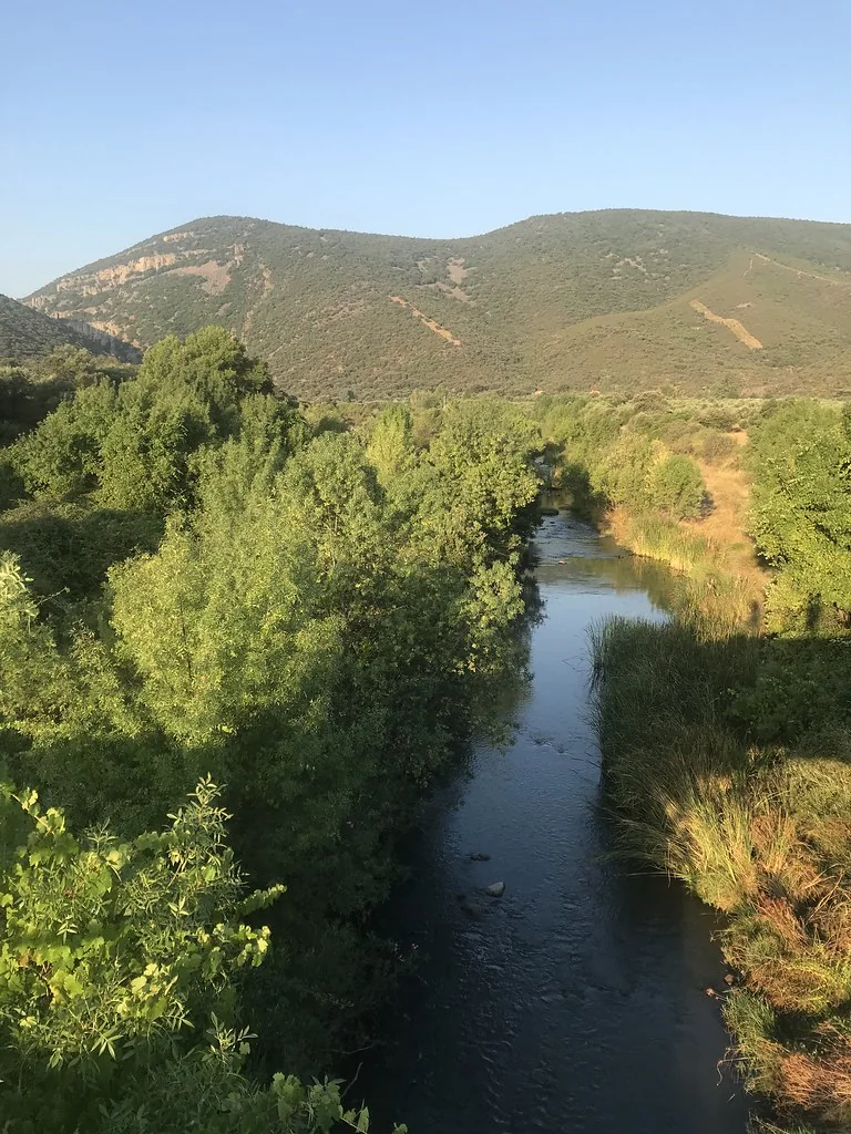 Curso de agua entre vegetación de ribera y sierras