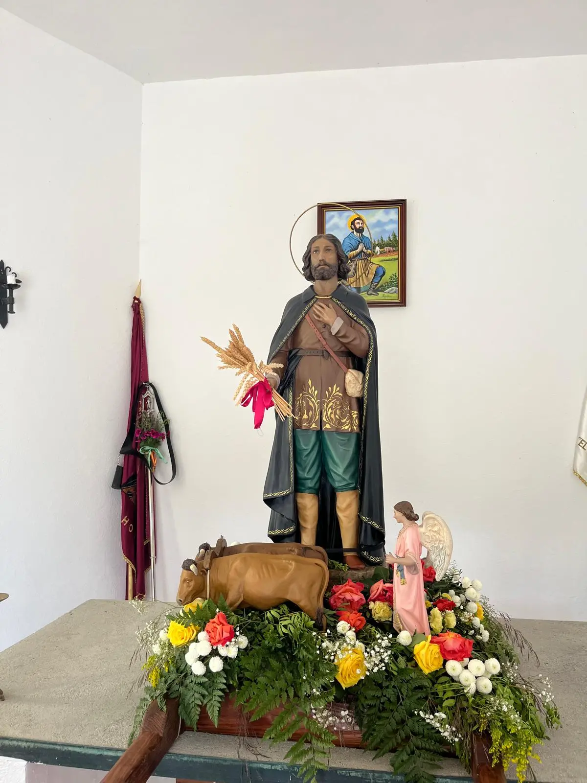 Imagen completa de San Isidro adornada con flores dentro de su ermita